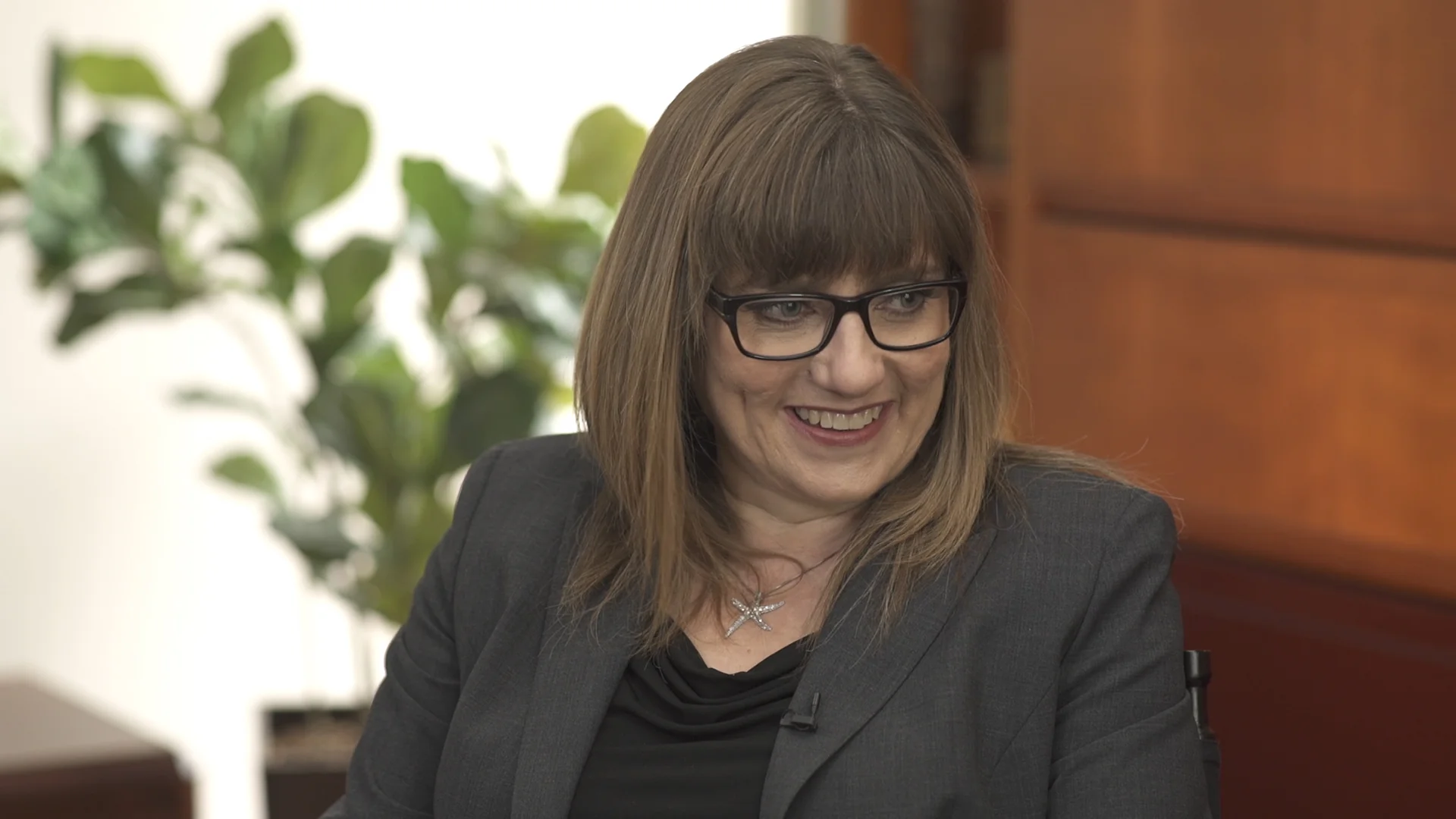 The interview. A woman in a dark blazer, seated, mid-answer — a finished frame from the film.