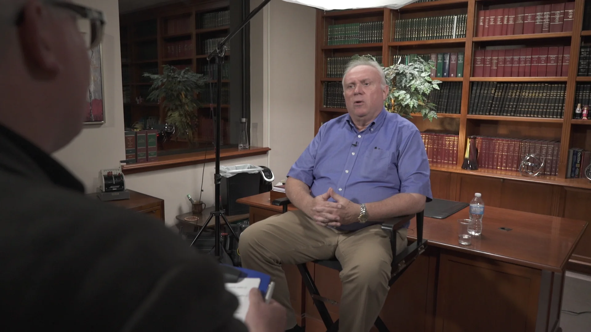The room. The interview in progress with the operator on the second camera; bookshelves behind.