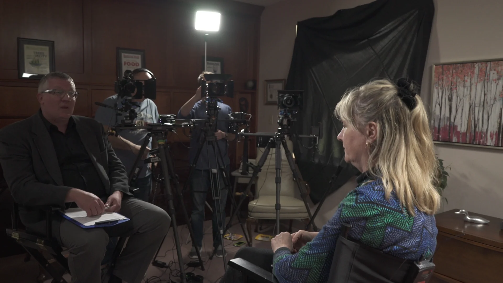 The set. Cameras and lighting on a dressed location, a wall sign in the background.