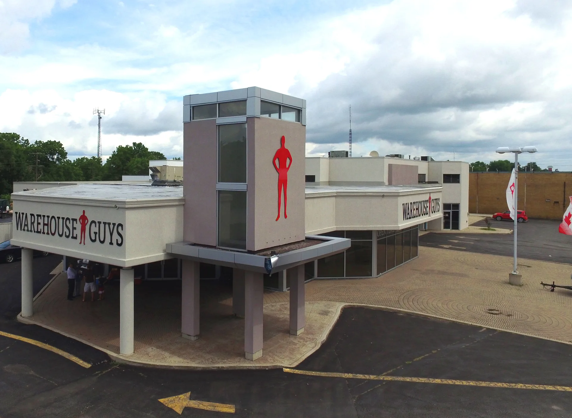The mascot. The store from the side, with the big red silhouette of a man on the facade — the character the series is built around.