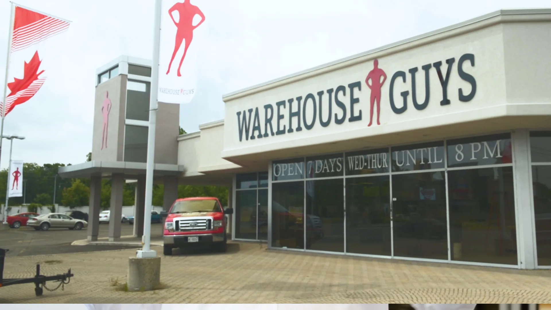 The store, on camera. A frame from the edit — the frontage, "open 7 days a week", the Canadian flag, the lot.