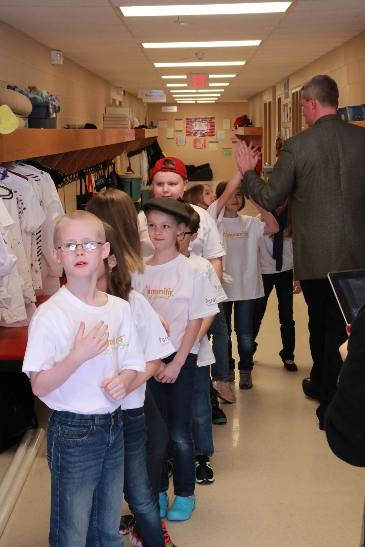 The cast. Children in white "Community" t-shirts in a school hallway — the film's own audience before the shoot.