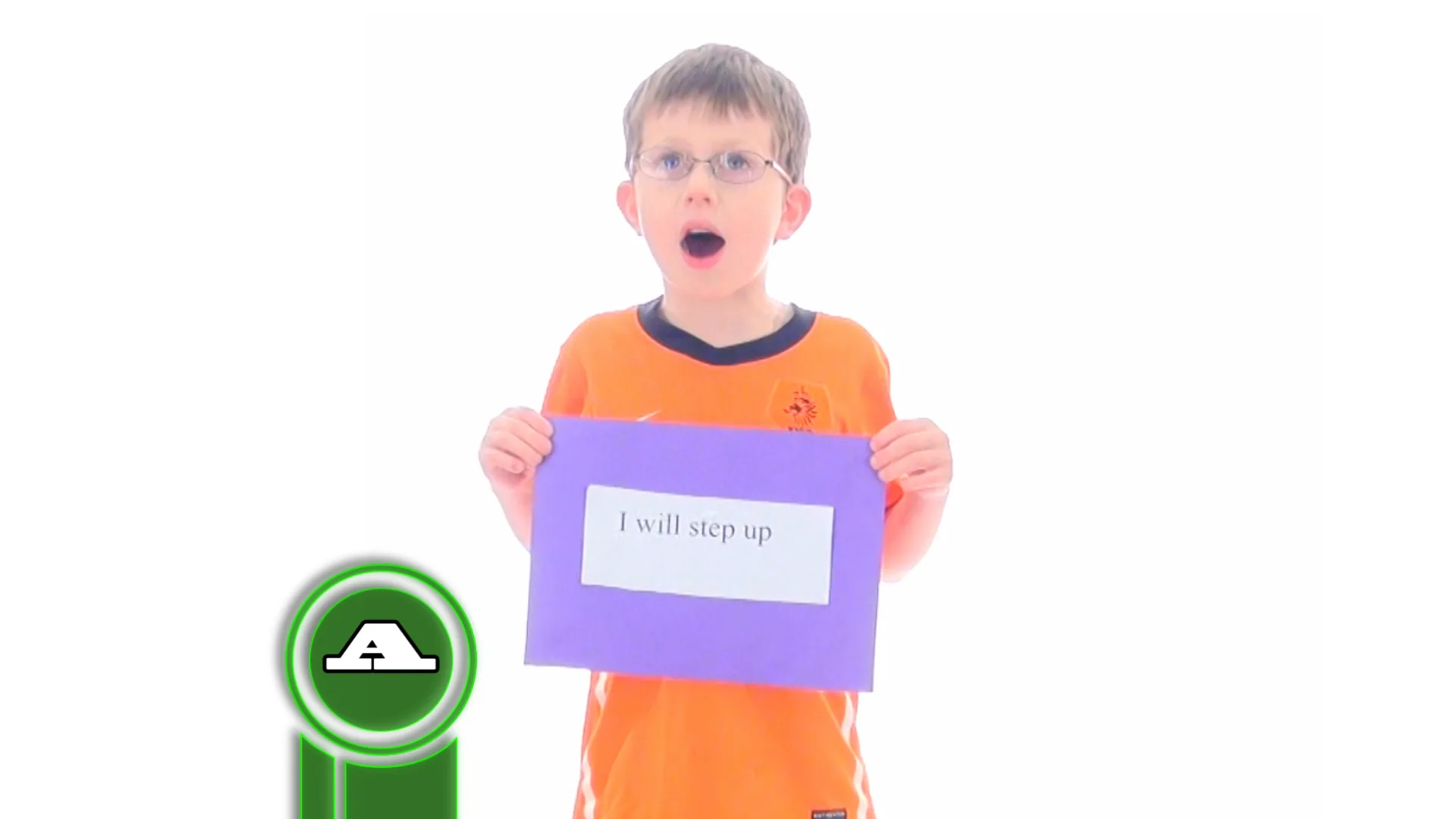A boy wearing glasses holds up a sign reading “I will step up” against a plain white backdrop.