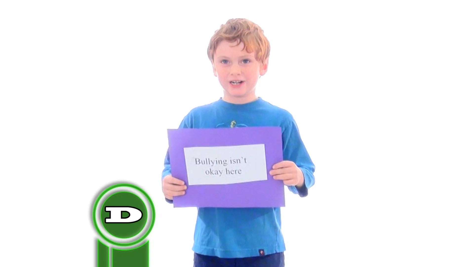 A child in a blue shirt holds a sign reading “Bullying isn’t okay here” on a white backdrop, with green ring-shaped logo elements beside them.