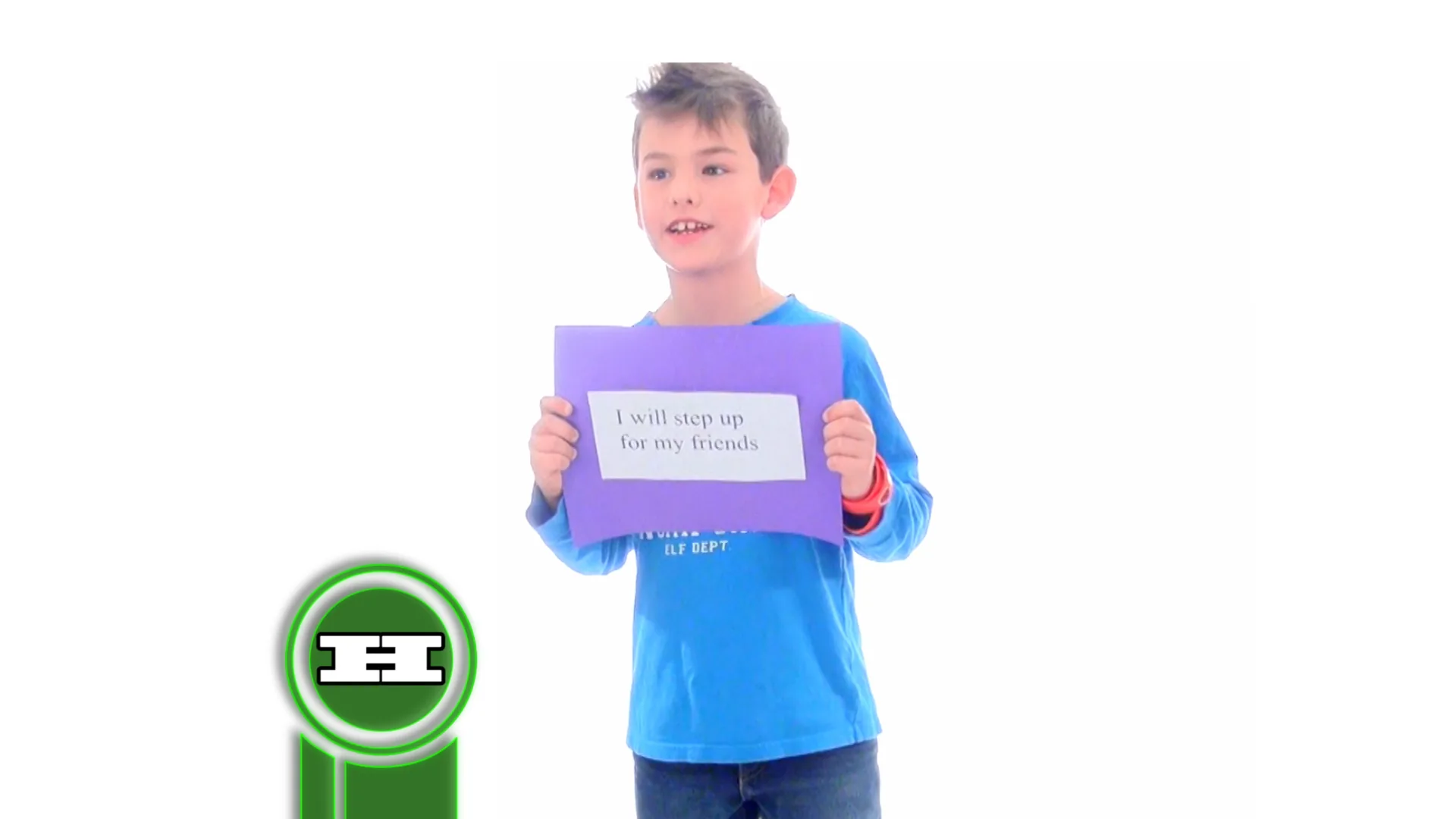 A boy holds a sign reading “I will step up for my friends” against a plain white backdrop.