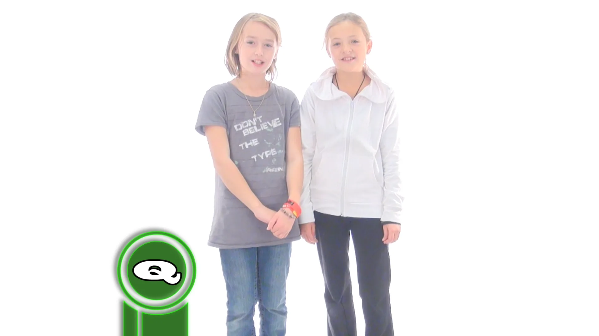 Two girls stand hand-in-hand before a white backdrop beside a circular green logo graphic; a shirt reads “DON’T BELIEVE THE …”, cut off at the edge.