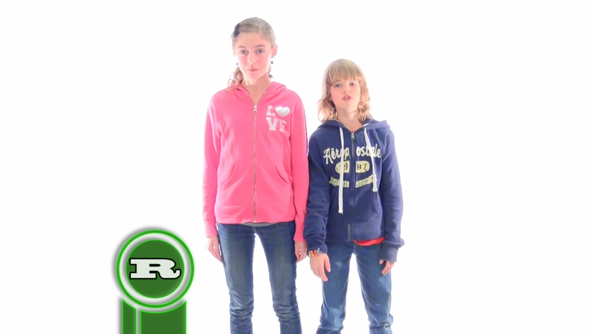 Two children in casual clothes — one in a pink hoodie, one in a blue hoodie — stand side by side against a white backdrop.