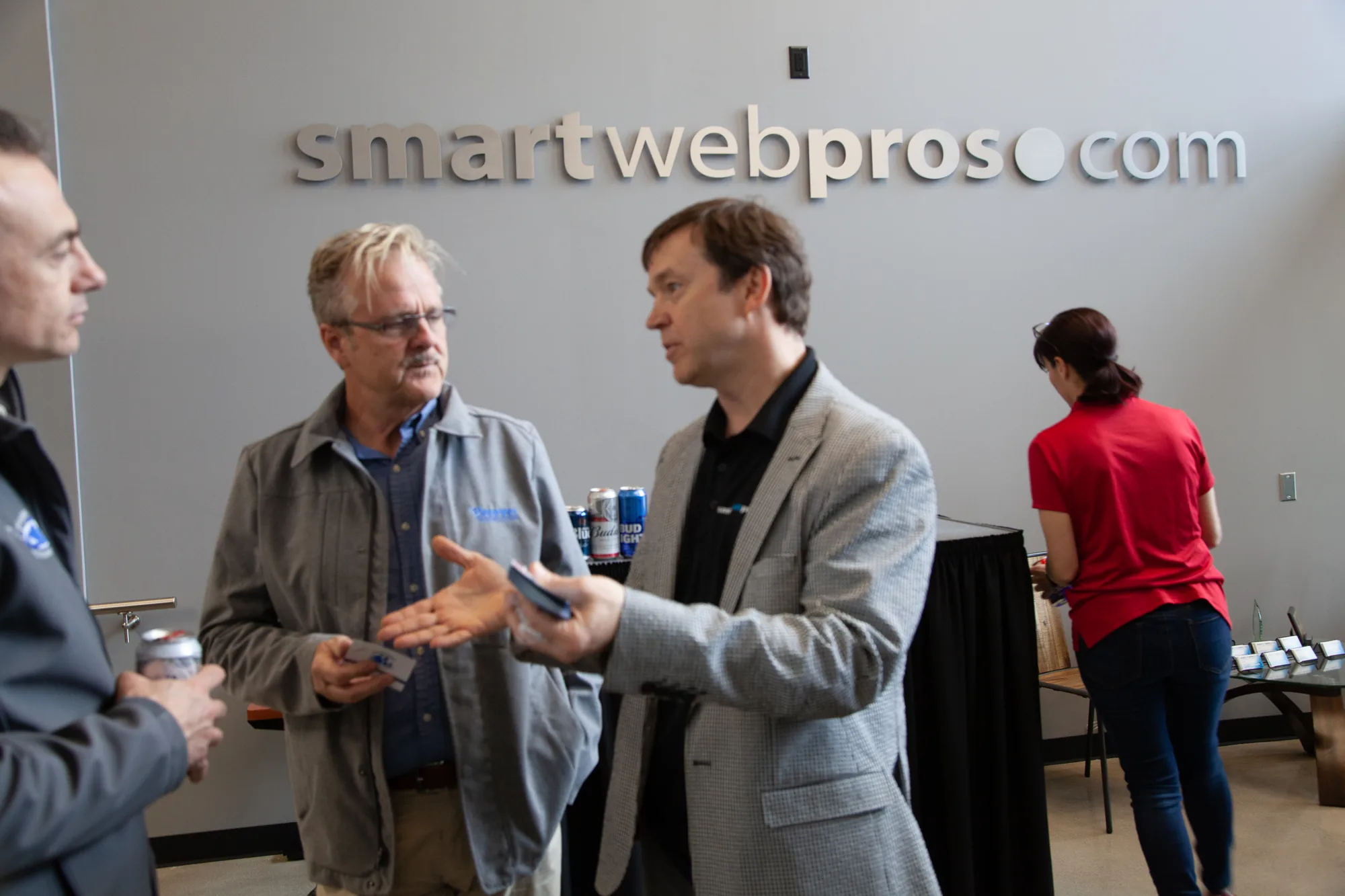 Two people talking, a business card changing hands, a third listening in.